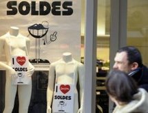 Des personnes passent devant une vitrine indiquant les soldes… © 2010 AFP Jean-Christophe Verhaegen